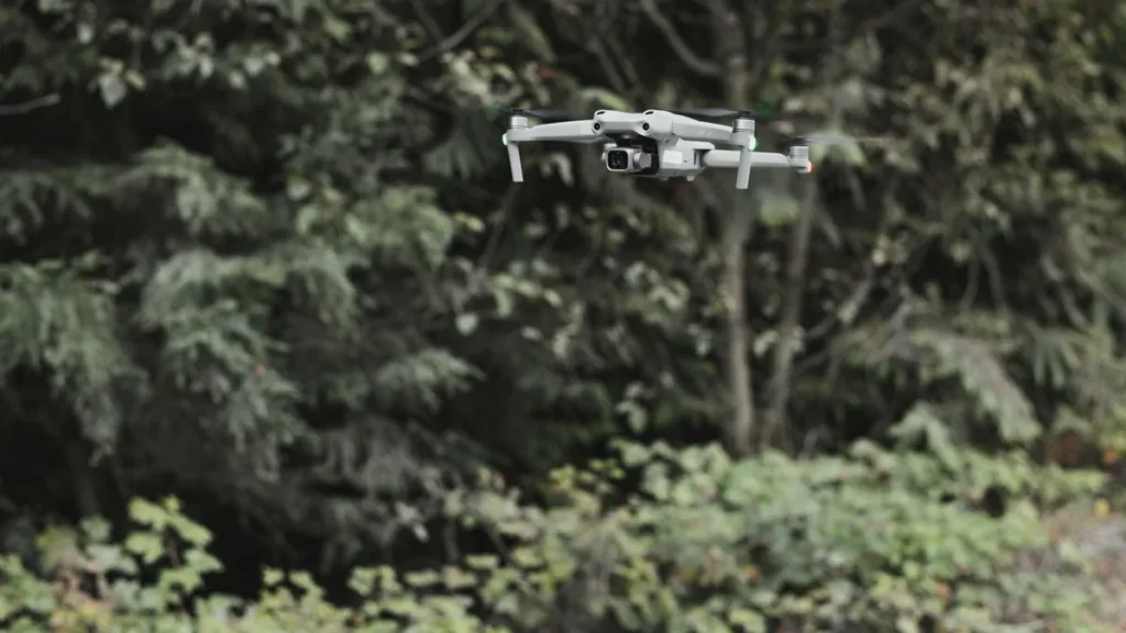 Do I Need an SFOC? 3 Clear Questions for Canadian Pilots 3 Folding drone hovering at a treeline, the lower-risk beyond visual line of sight work a Level 1 Complex certificate and an RPOC allow
